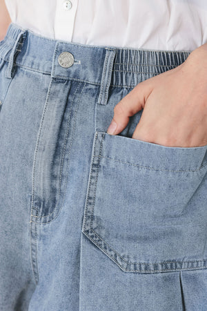 Woman wearing washed light denim short featuring elastic waist, front closure, front pockets and pleats with wide leg | FREEMARKET