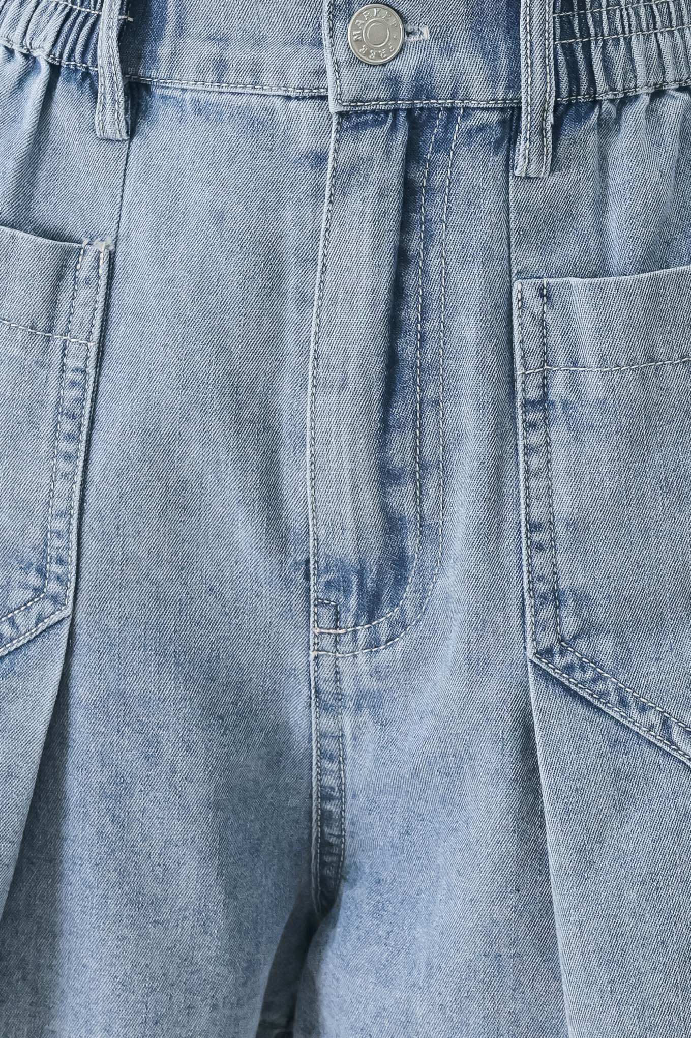 Close up of a washed light denim short featuring elastic waist, front closure, front pockets and pleats with wide leg | FREEMARKET