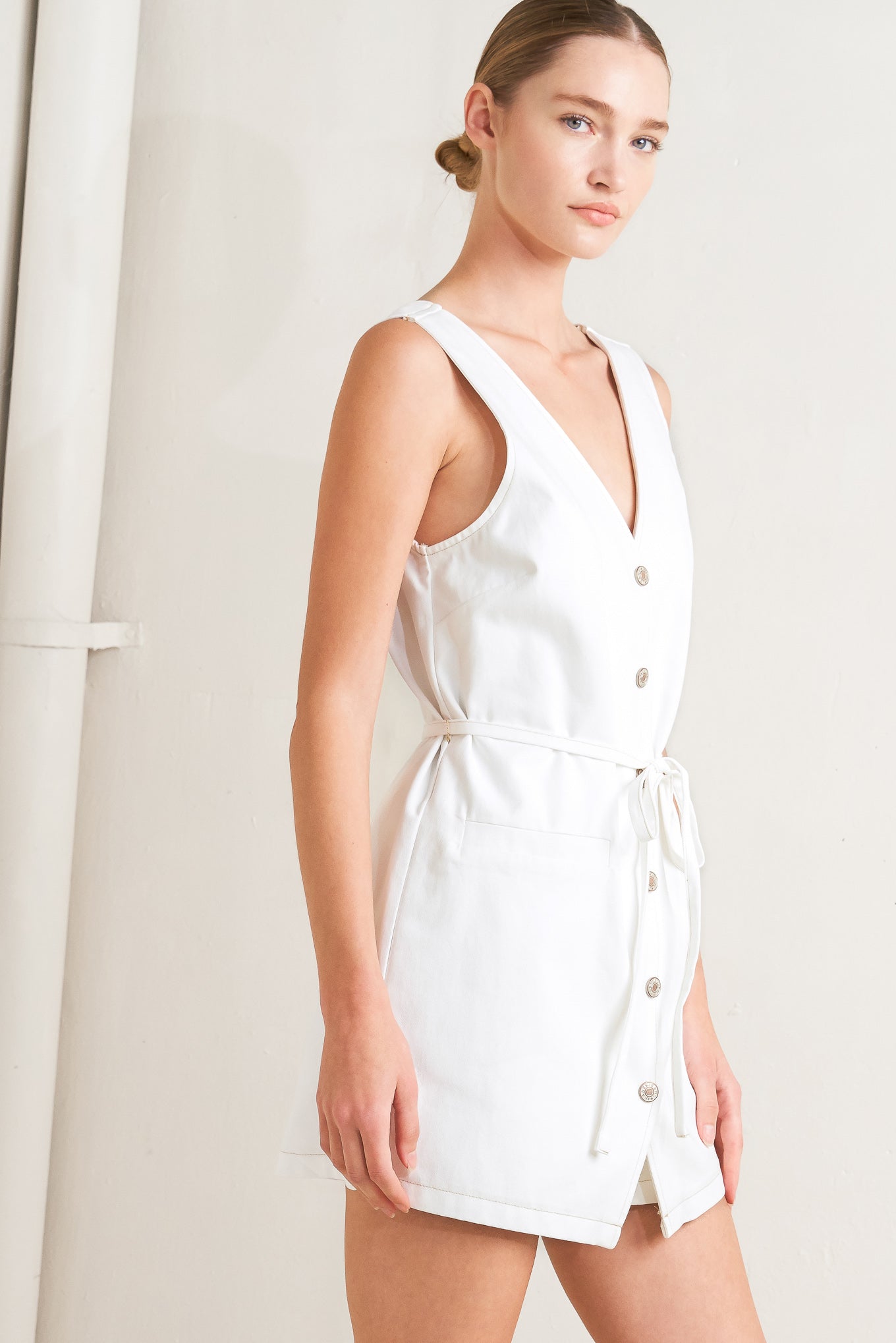 A solid woven romper featuring V neckline, sleeveless, front button down, pockets and skinny self belt

Details:

Self: 100% Cotton

Size & Fit

- Model is 5`8" And Wearing Size Small
- Measurements Taken From Size Small
- Approx. Length: 33"