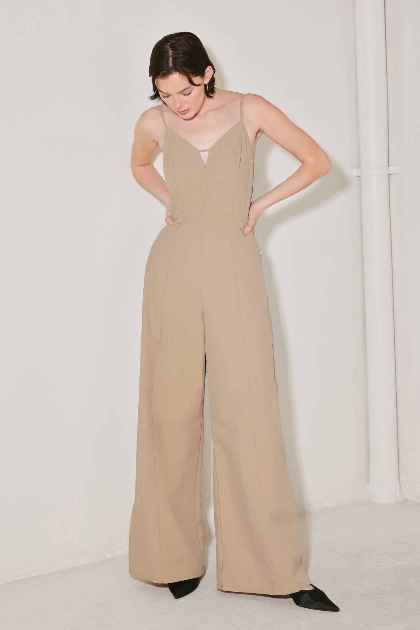 Woman wearing a beige jumpsuit featuring cami top, straps, contrasting belt, wide leg and back zipper closure | FREEMARKET | Flying Tomato