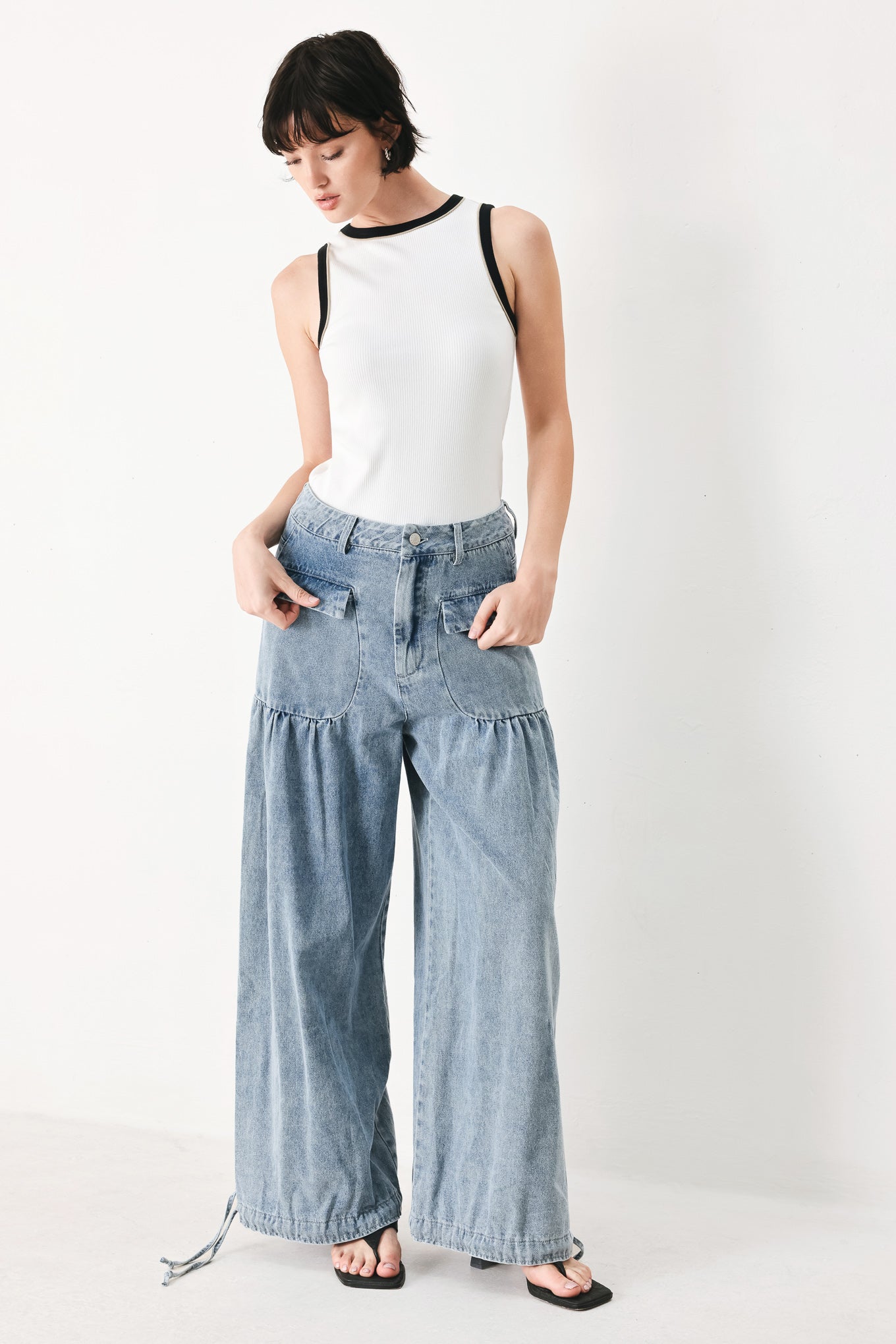 Woman wearing washed denim pants featuring front closure, front pockets, balloon leg with bottom tie | FREEMARKET