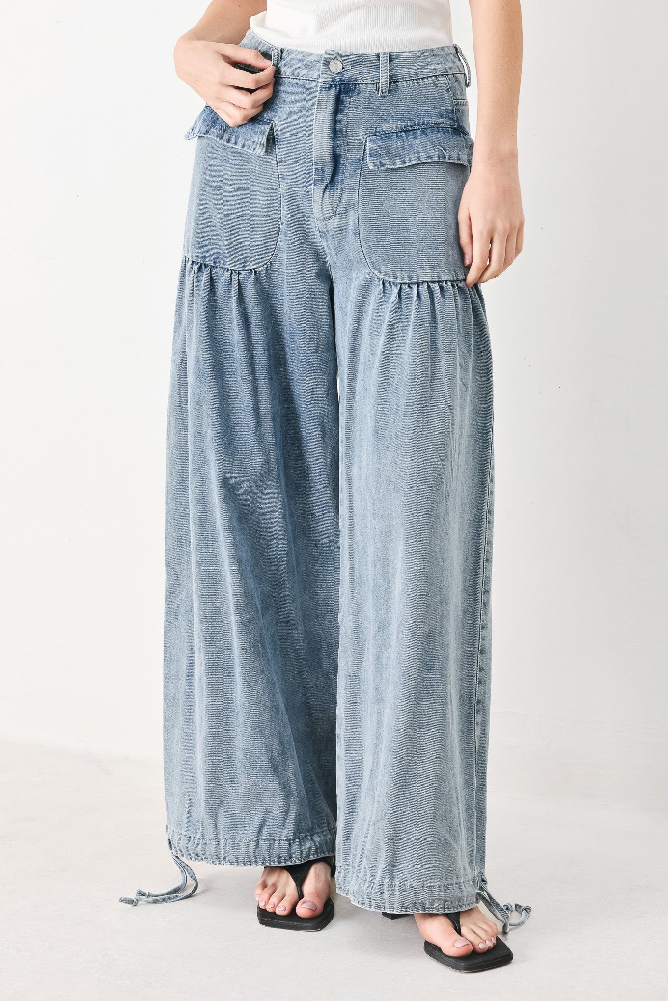 Woman wearing washed denim pants featuring front closure, front pockets, balloon leg with bottom tie | FREEMARKET