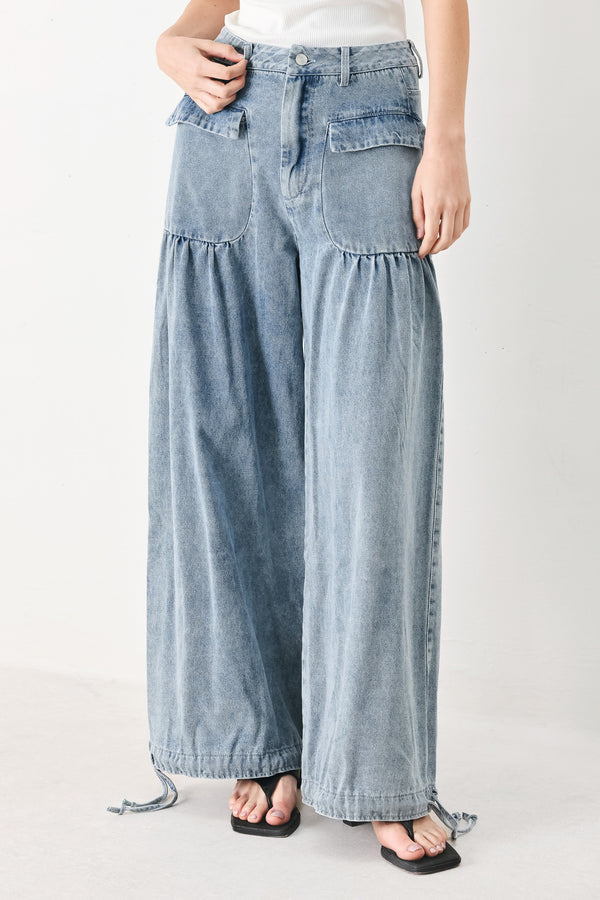 Woman wearing washed denim pants featuring front closure, front pockets, balloon leg with bottom tie | FREEMARKET