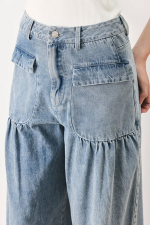Woman wearing washed denim pants featuring front closure, front pockets, balloon leg with bottom tie | FREEMARKET