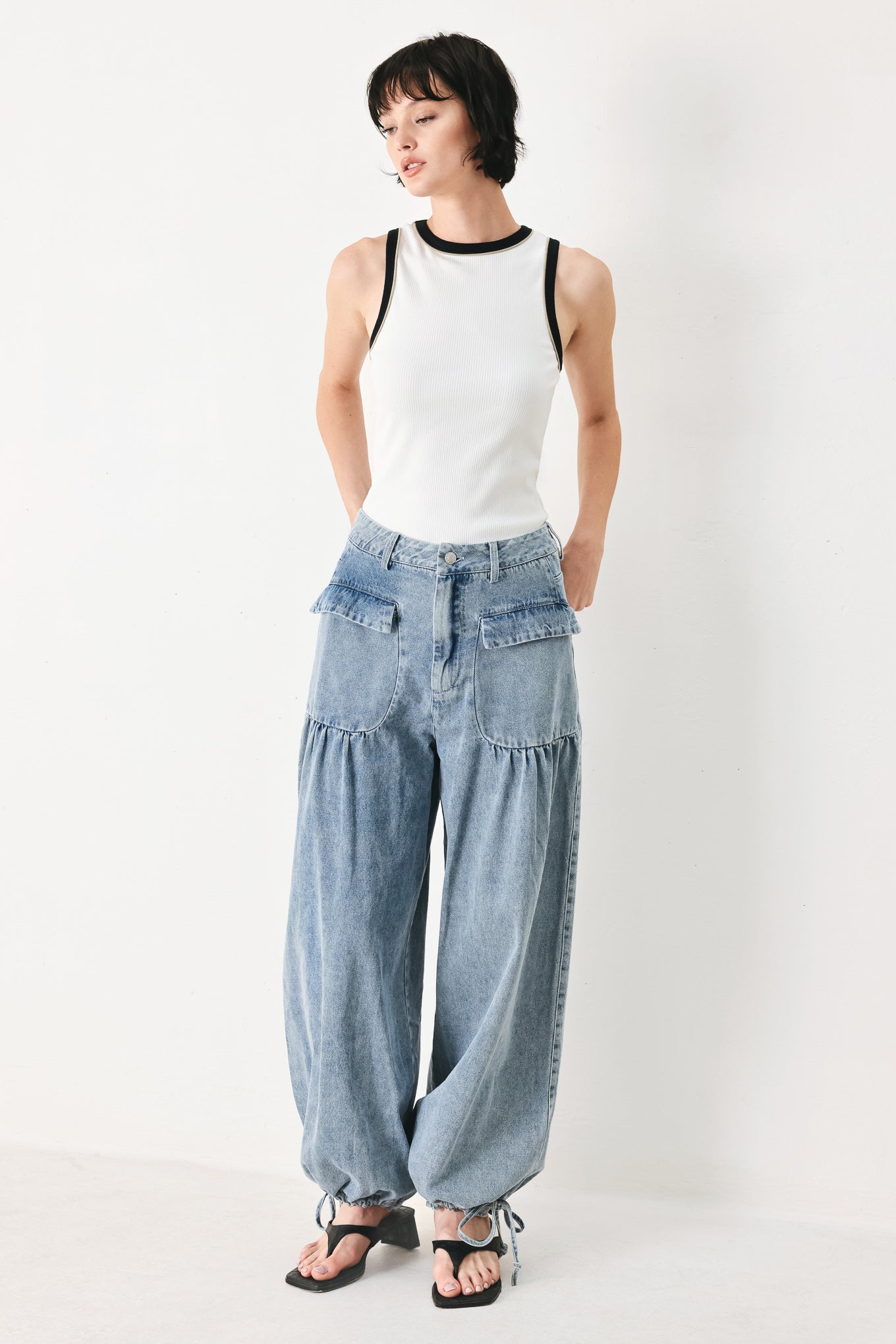 Woman wearing washed denim pants featuring front closure, front pockets, balloon leg with bottom tie | FREEMARKET