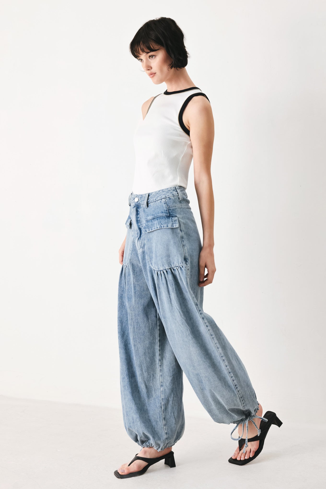 Woman wearing washed denim pants featuring front closure, front pockets, balloon leg with bottom tie | FREEMARKET