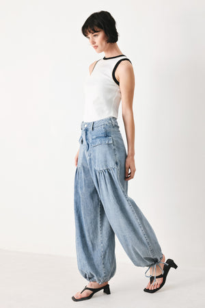 Woman wearing washed denim pants featuring front closure, front pockets, balloon leg with bottom tie | FREEMARKET