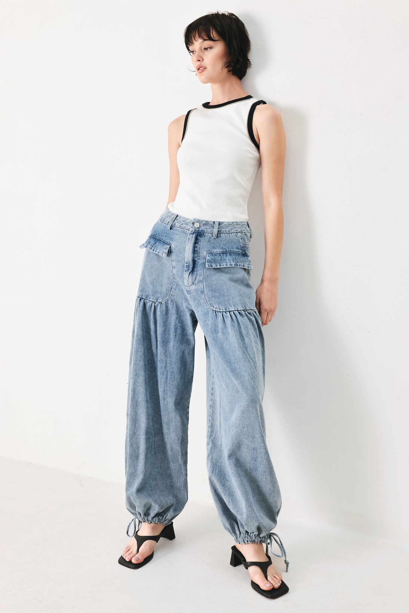 Woman wearing washed denim pants featuring front closure, front pockets, balloon leg with bottom tie | FREEMARKET