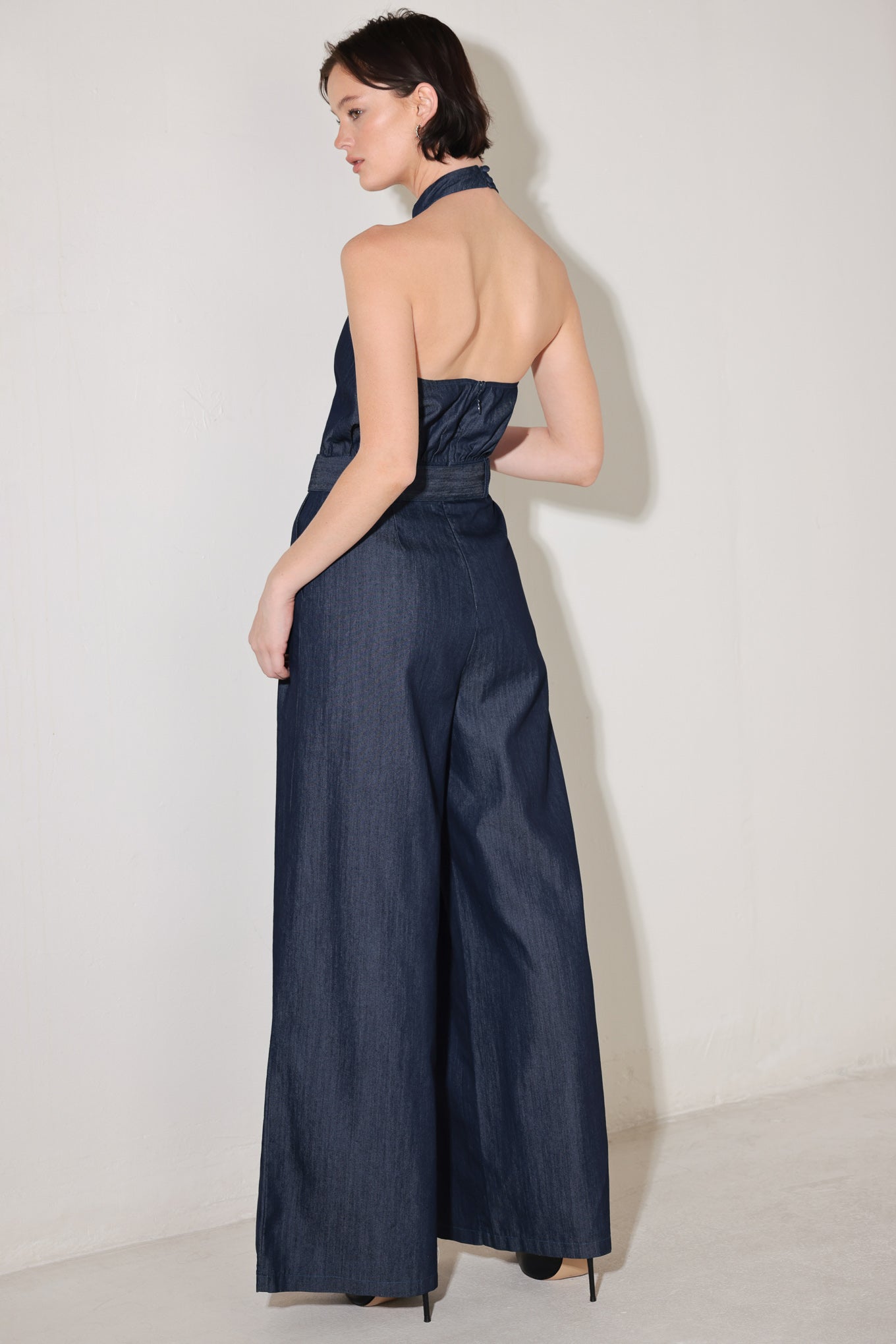 
A solid woven jumpsuit featuring halter neckline, self belt, wide leg, back neck button closure, bare back with straps and zipper closure

Details:

Self : 72% Cotton 28% Polyester
Lining : 100% Polyester

Size &amp; Fit

- Model is 5`8" And Wearing Size Small
- Measurements Taken From Size Small
- Approx. Length: 61"
