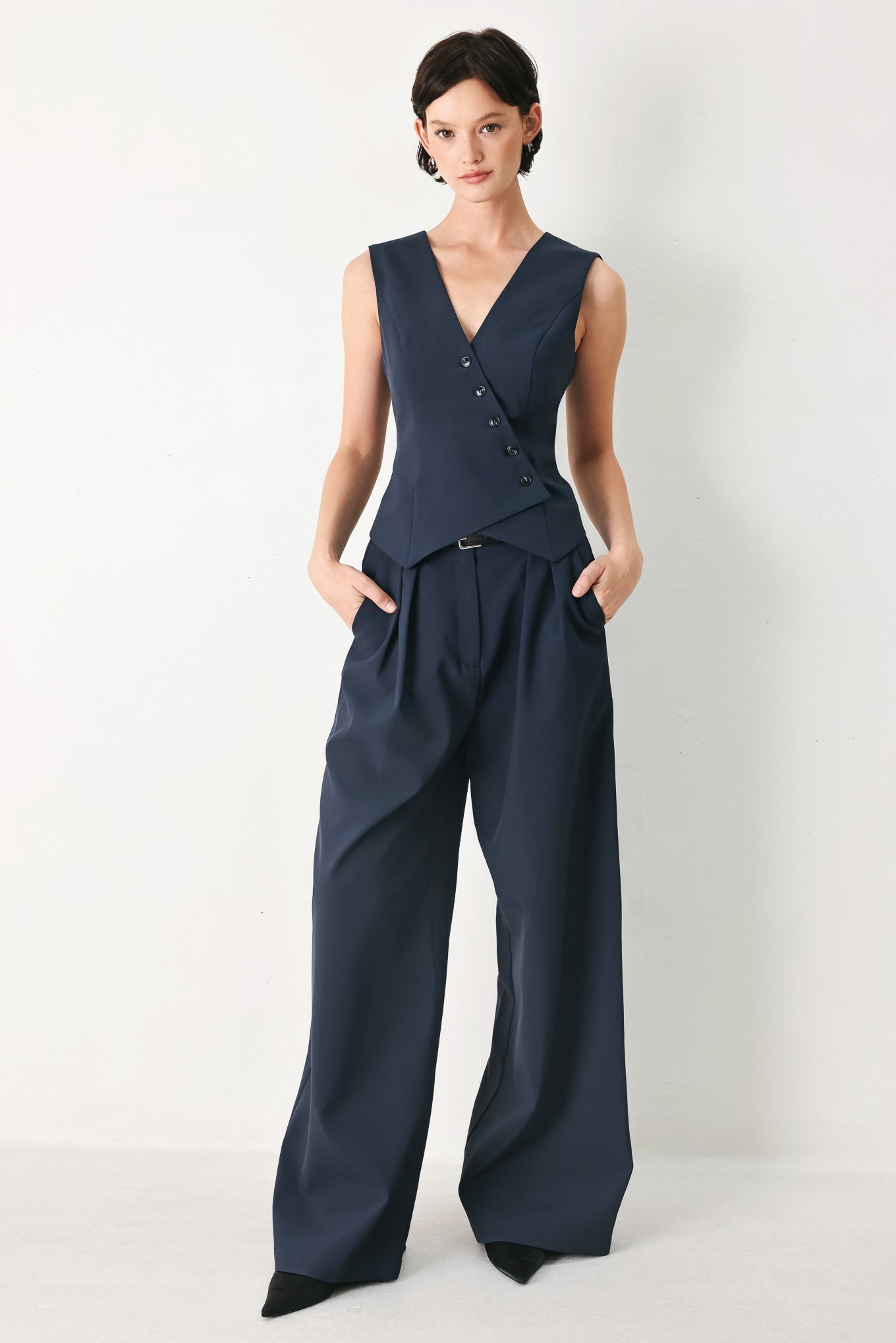 Woman wearing navy pleated pants with a black belt | FREEMARKET