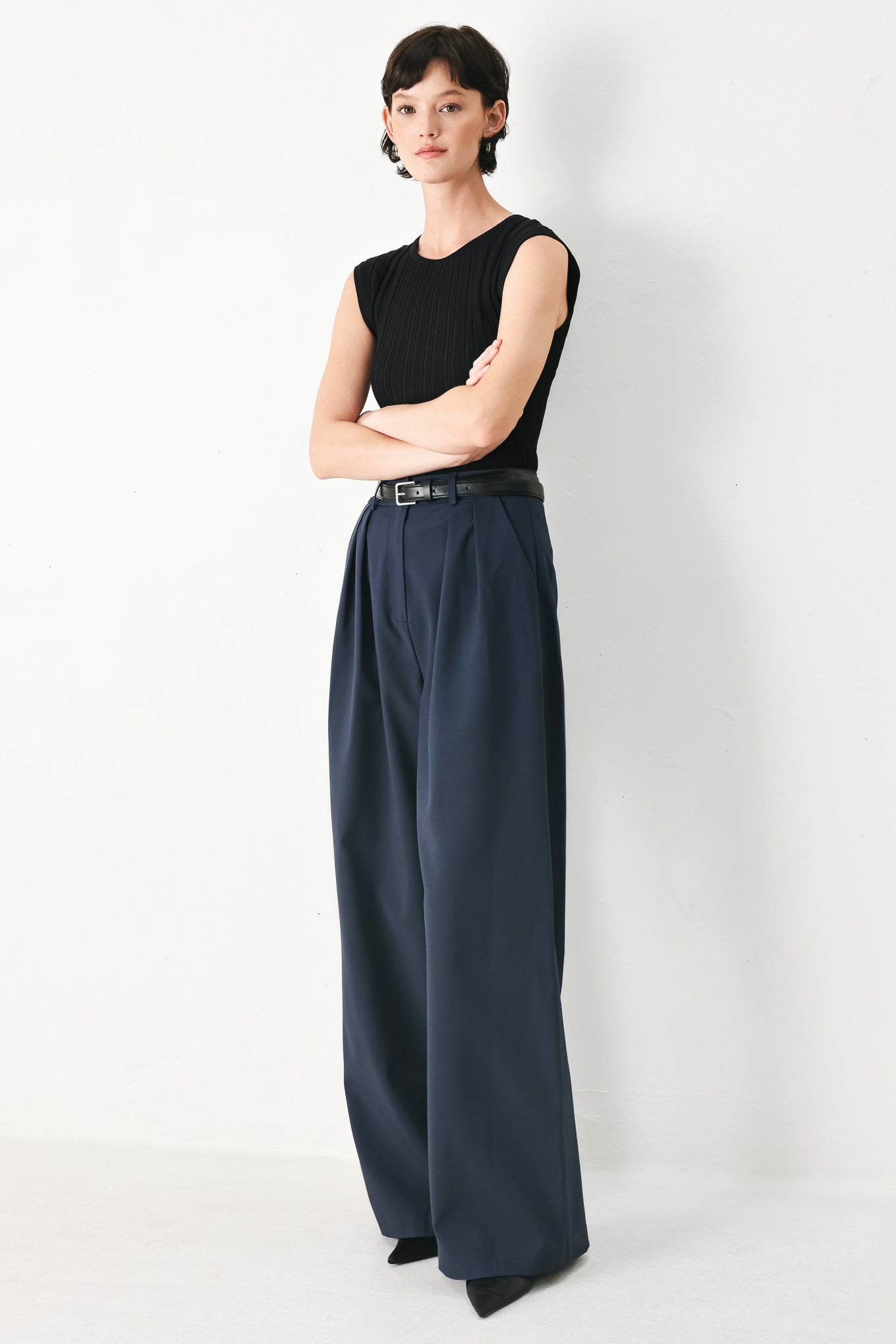 Woman wearing navy pleated pants with a black belt | FREEMARKET