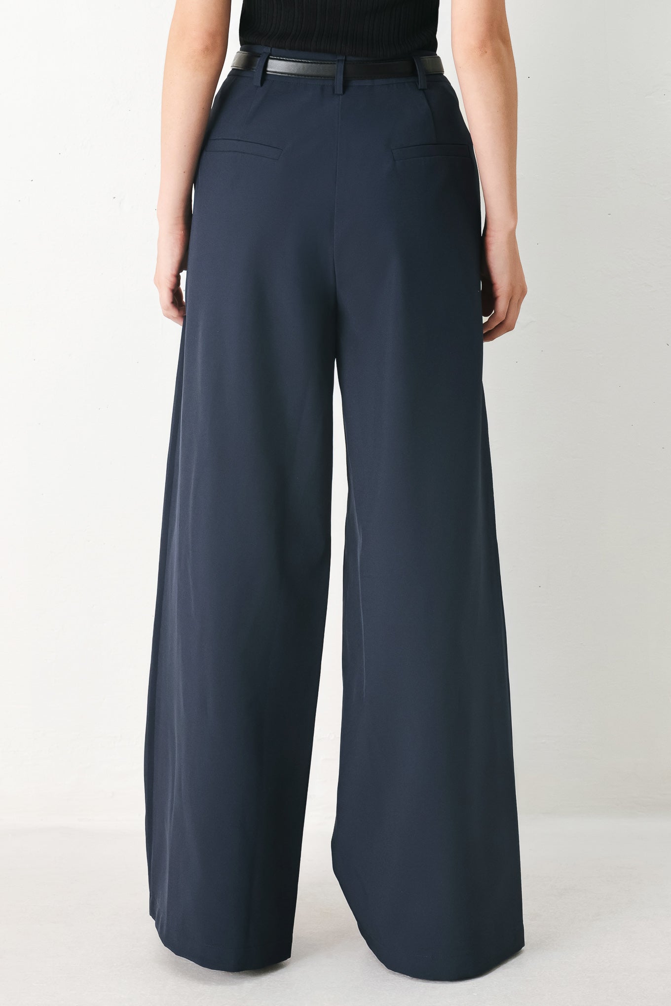 Woman wearing navy pleated pants with a black belt | FREEMARKET