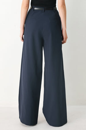 Woman wearing navy pleated pants with a black belt | FREEMARKET