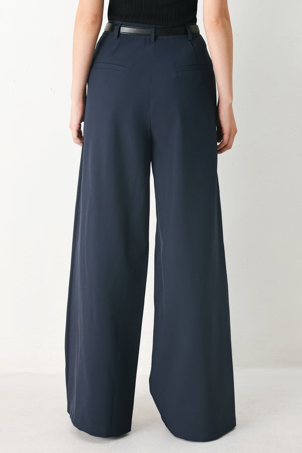 Woman wearing navy pleated pants with a black belt | FREEMARKET