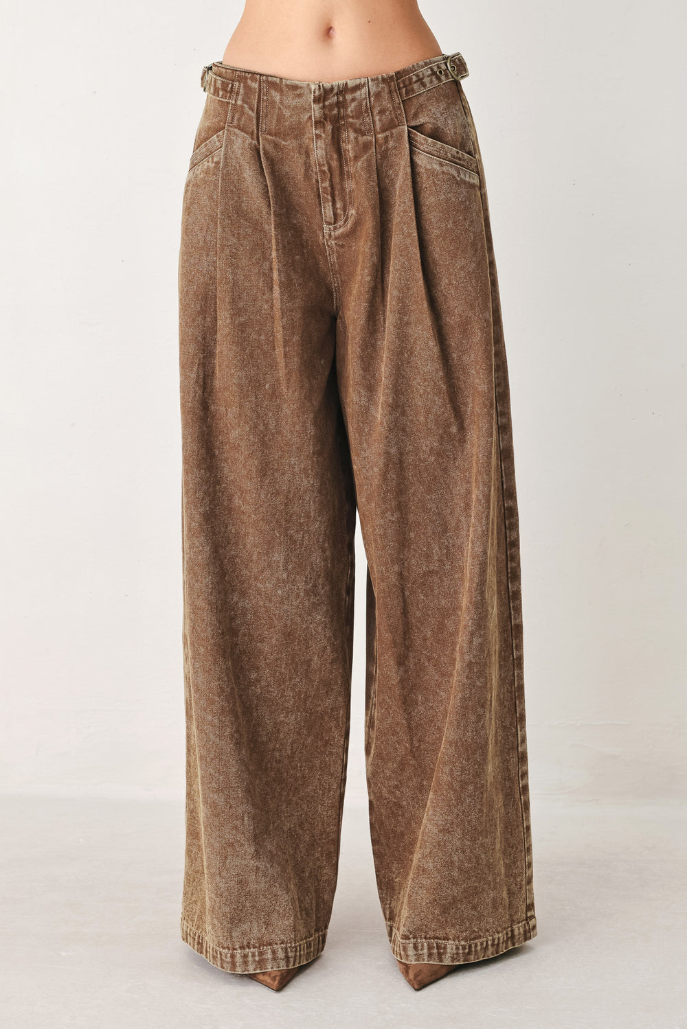 Woman wearing a washed brown denim pant featuring front closure, pockets and side buckle detail at waist | FREEMAKET
