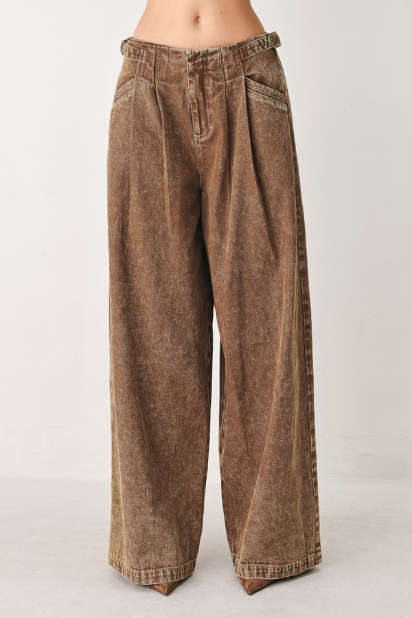 Woman wearing a washed brown denim pant featuring front closure, pockets and side buckle detail at waist | FREEMAKET