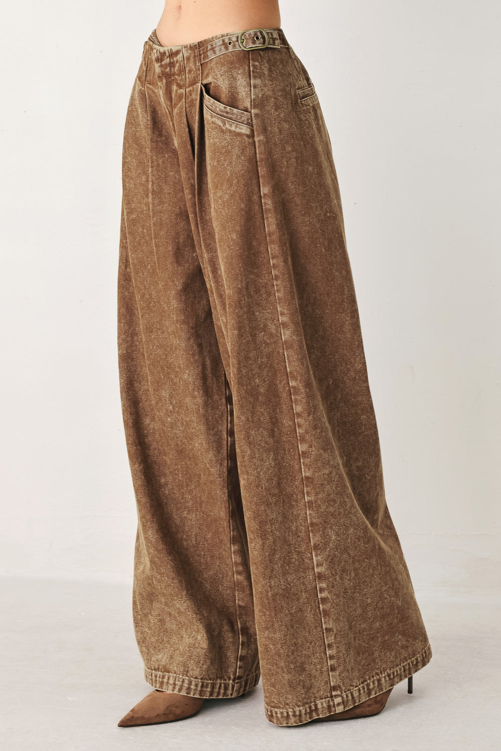 Woman wearing a washed brown denim pant featuring front closure, pockets and side buckle detail at waist | FREEMAKET