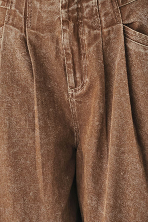 Woman wearing a washed brown denim pant featuring front closure, pockets and side buckle detail at waist | FREEMAKET