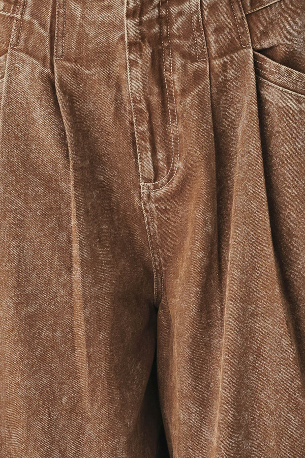 Woman wearing a washed brown denim pant featuring front closure, pockets and side buckle detail at waist | FREEMAKET