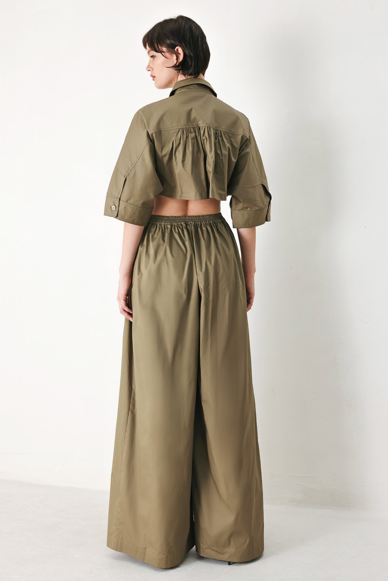 A solid woven matching utility-style jumpsuit consisting of a cropped, button-up shirt and high-waisted, wide-leg trouser