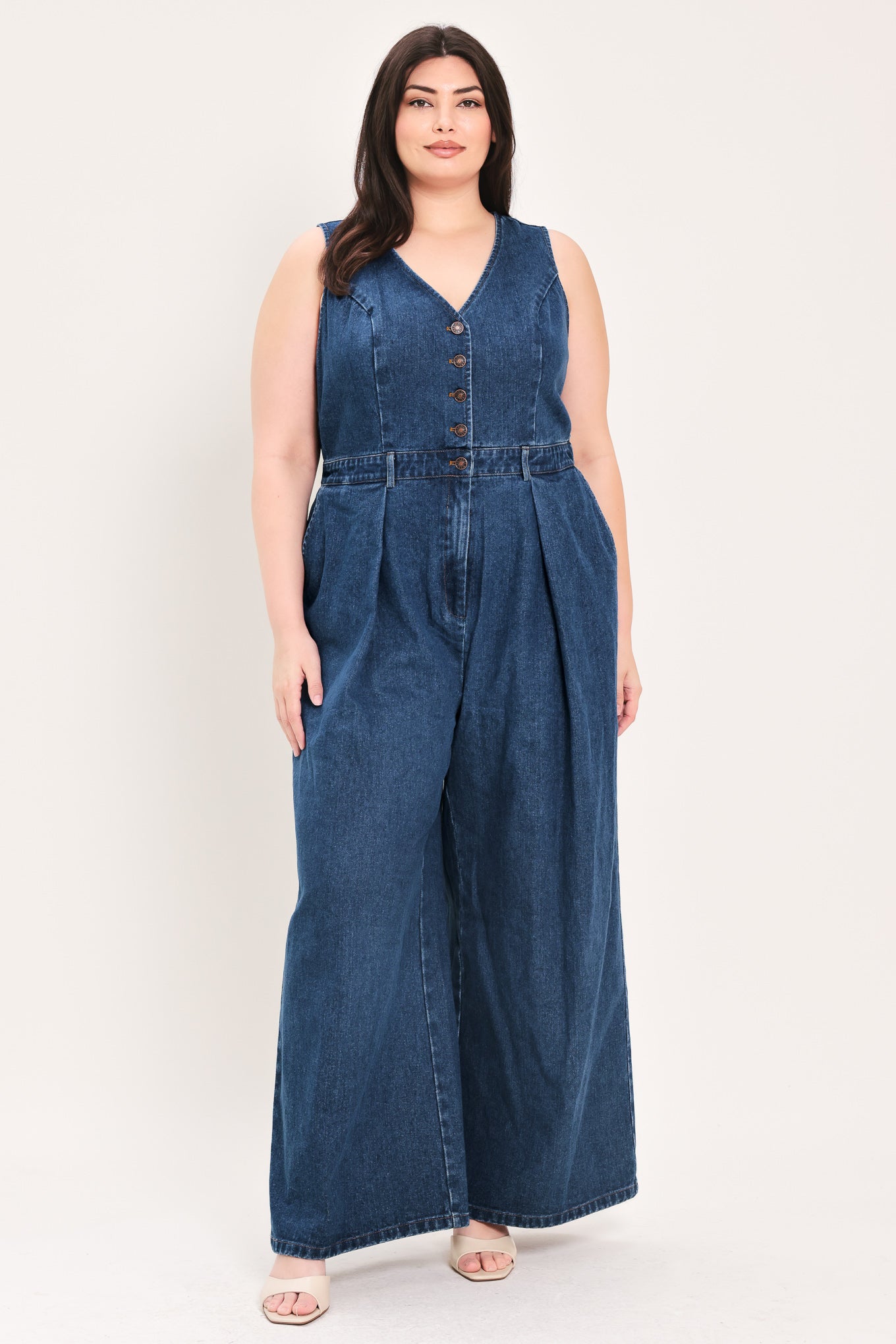 Woman wearing a denim jumpsuit featuring V neckline, sleeveless, front button closure, side pockets, wide leg | FREEMARKET Curve