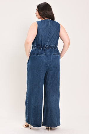 Woman wearing a denim jumpsuit featuring V neckline, sleeveless, front button closure, side pockets, wide leg | FREEMARKET Curve
