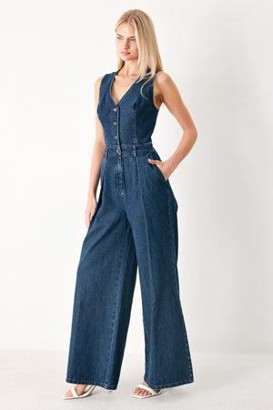 Woman wearing a denim jumpsuit featuring V neckline, sleeveless, front button closure, side pockets, wide leg and surplice back with cut out | FREEMARKET