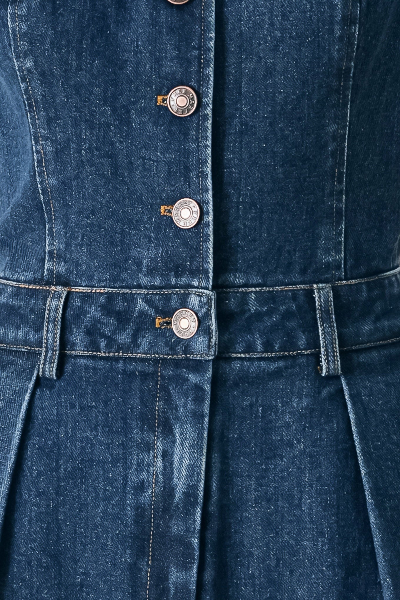 Close up of a denim jumpsuit featuring V neckline, sleeveless, front button closure, side pockets, wide leg and surplice back with cut out | FREEMARKET