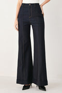 Woman wearing dark flared leg denim pants with front closure and cuff hem | FREEMARKET