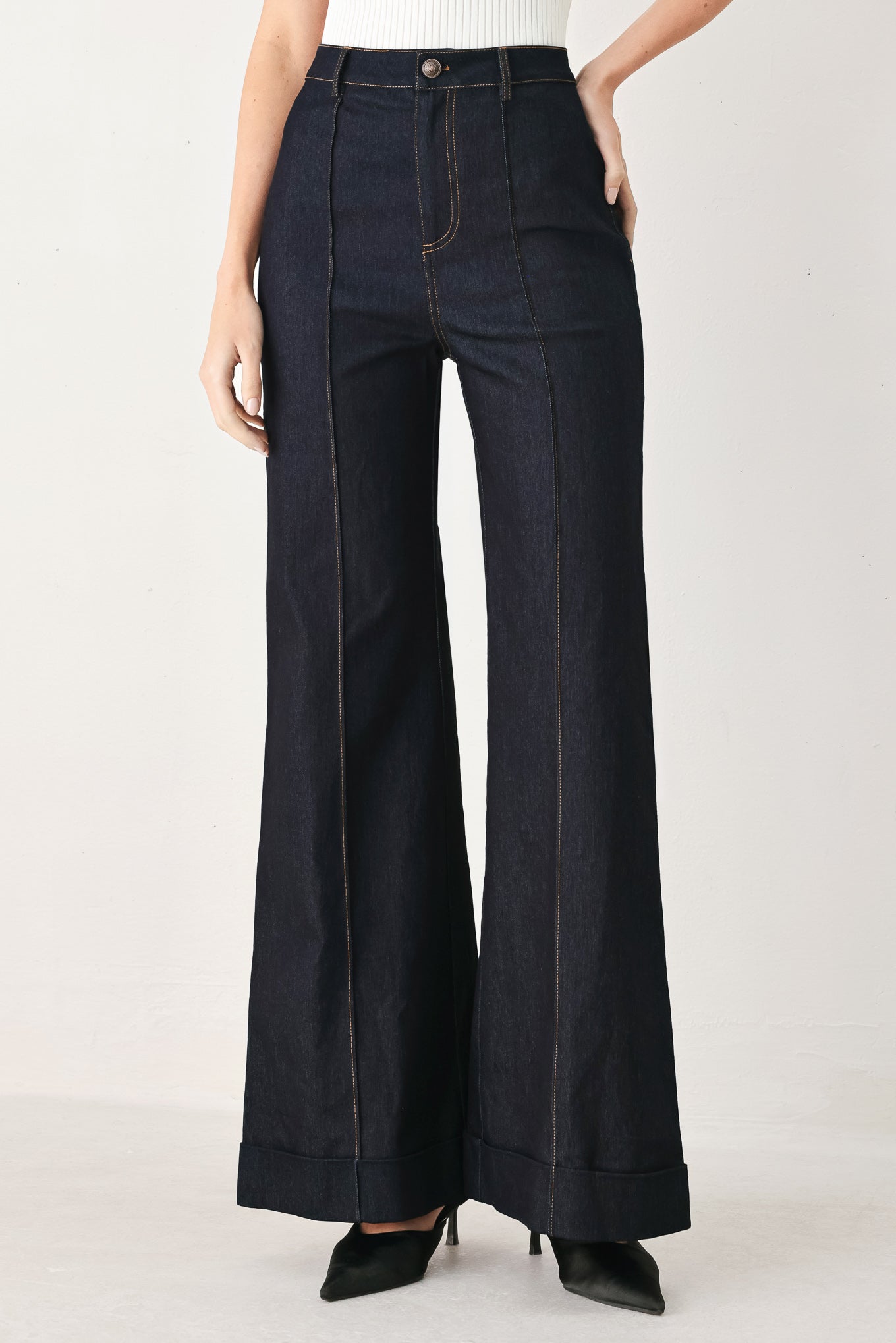 Woman wearing dark flared leg denim pants with front closure and cuff hem | FREEMARKET