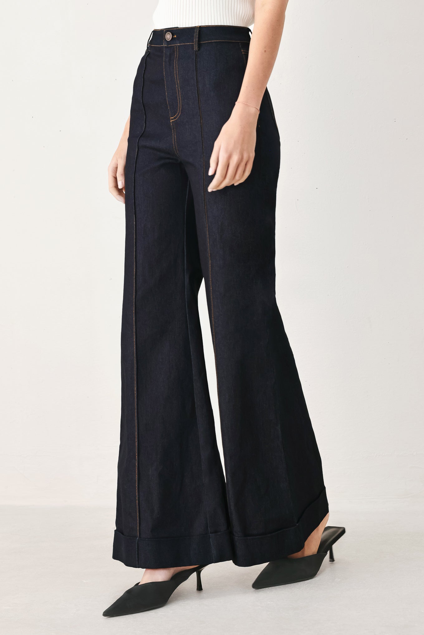Woman wearing dark flared leg denim pants with front closure and cuff hem | FREEMARKET
