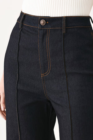 Woman wearing dark flared leg denim pants with front closure and cuff hem | FREEMARKET