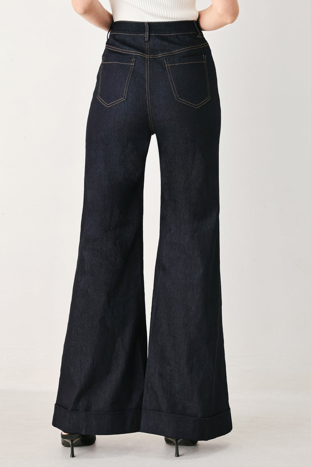 Woman wearing dark flared leg denim pants with front closure and cuff hem | FREEMARKET