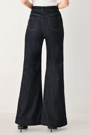 Woman wearing dark flared leg denim pants with front closure and cuff hem | FREEMARKET