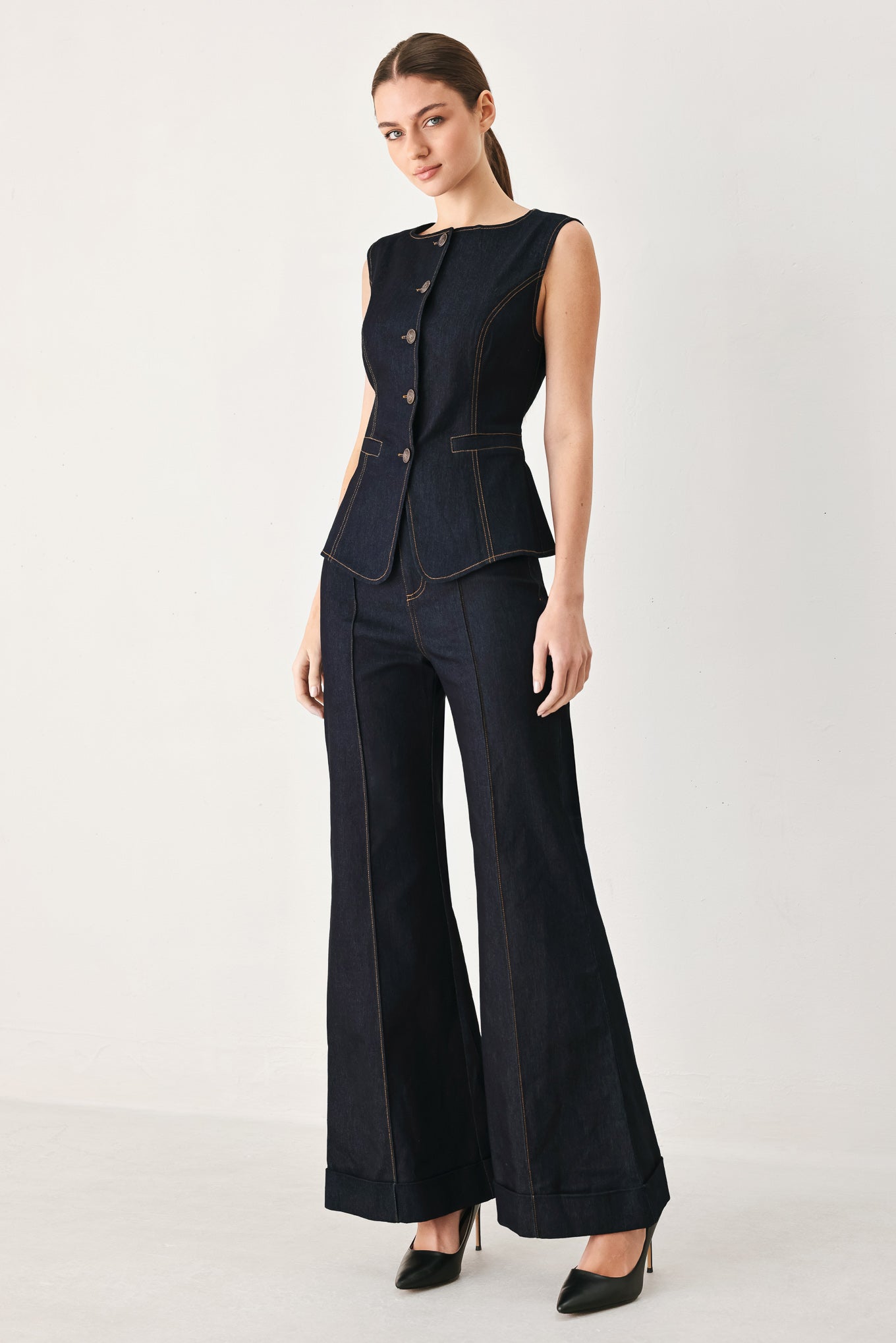 Woman wearing dark flared leg denim pants with front closure and cuff hem | FREEMARKET