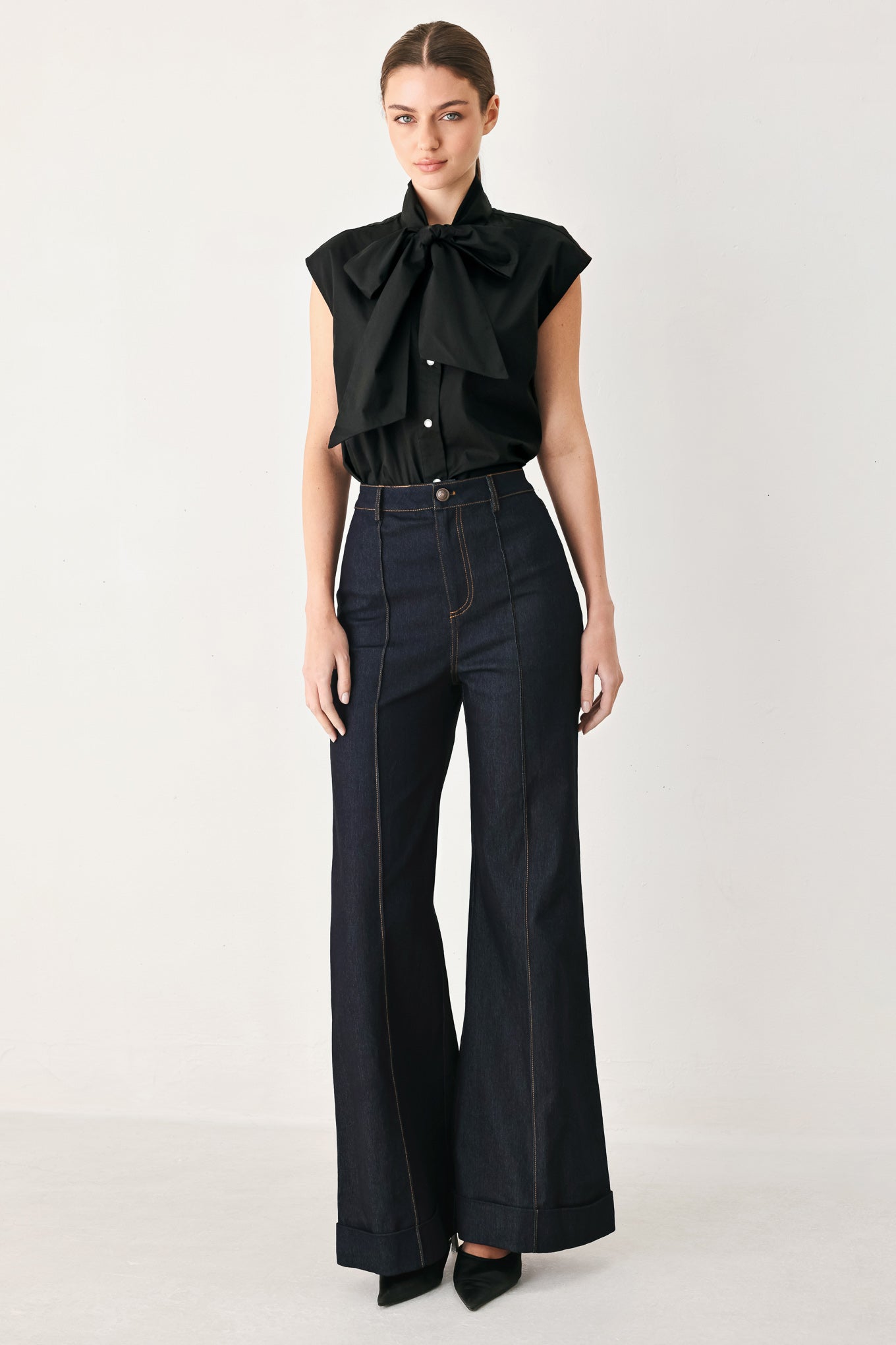 Woman wearing dark flared leg denim pants with front closure and cuff hem | FREEMARKET
