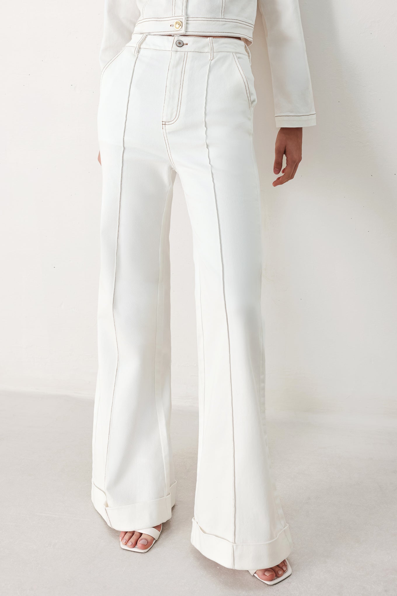 Woman wearing white wide-leg pants with a seam down the middle of each leg | FREEMARKET