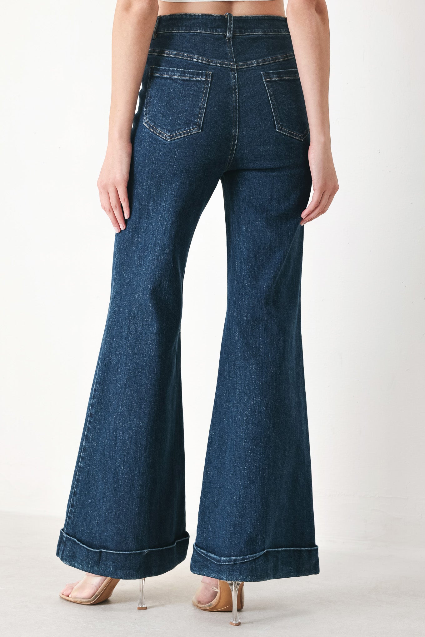 Woman wearing dark blue flared jeans featuring front closure, pockets, center seam | FREEMARKET | Flying Tomato