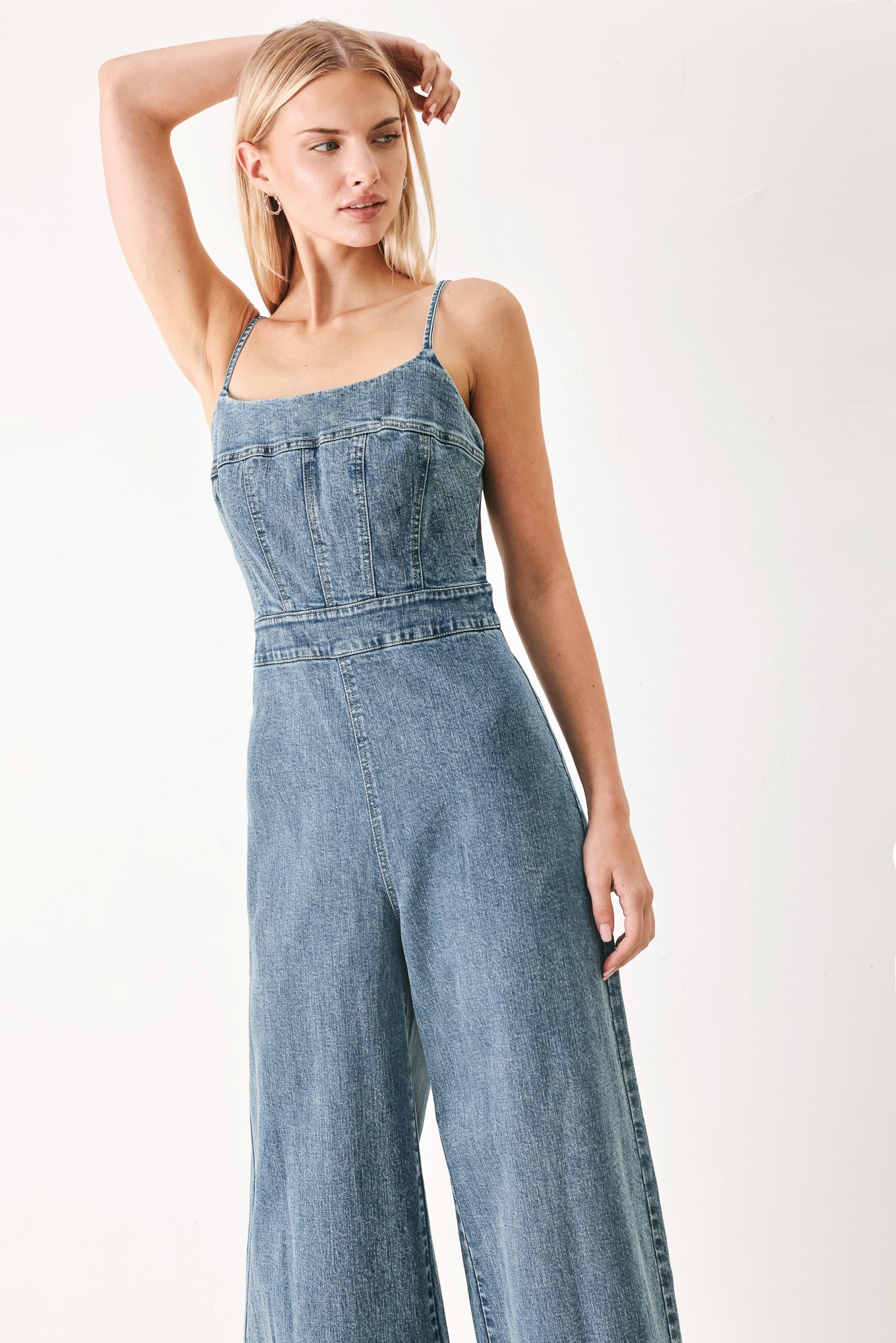 Woman wearing a denim jumpsuit featuring straight neckline, straps, wide leg and back zipper closure | FREEMARKET