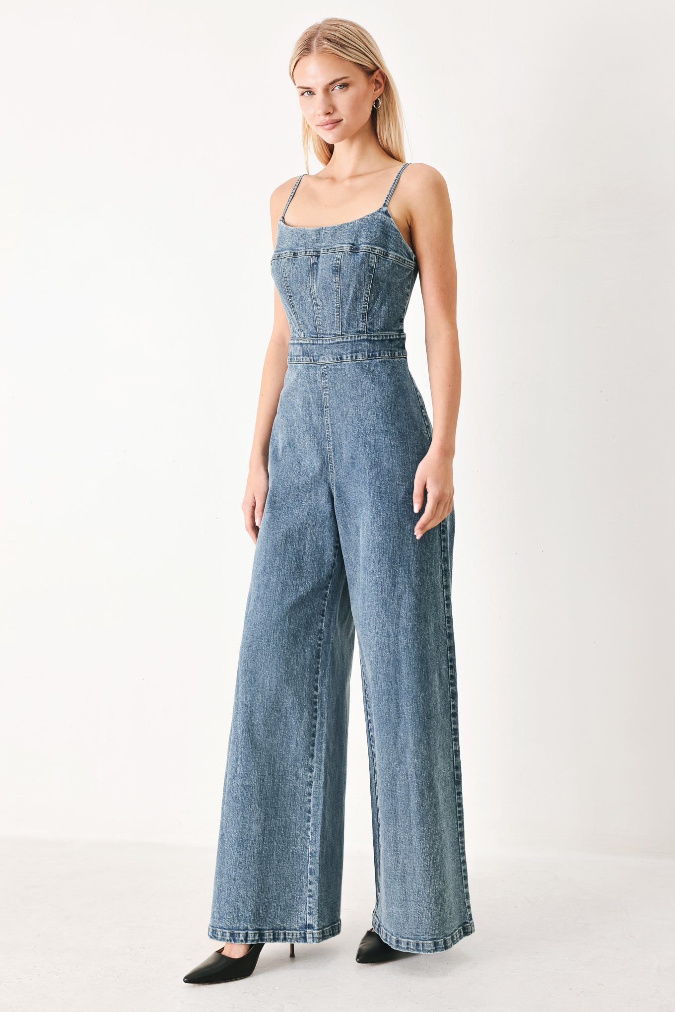Woman wearing a denim jumpsuit featuring straight neckline, straps, wide leg and back zipper closure | FREEMARKET