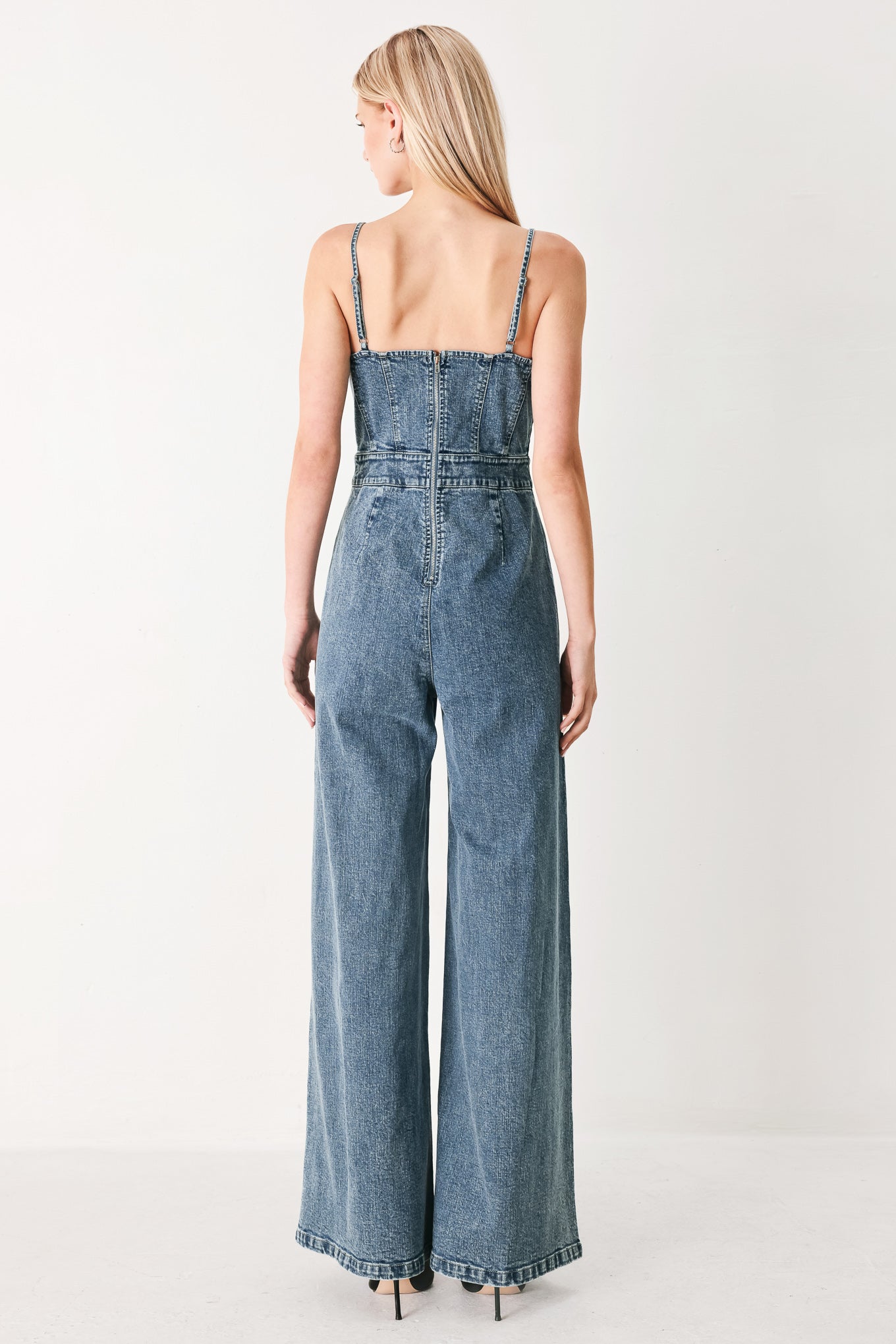 Woman wearing a denim jumpsuit featuring straight neckline, straps, wide leg and back zipper closure | FREEMARKET