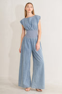 Woman wearing a denim jumpsuit featuring wide neckline, short sleeve, wide knit waistband, wide leg and back slit with button closure | FREEMARKET