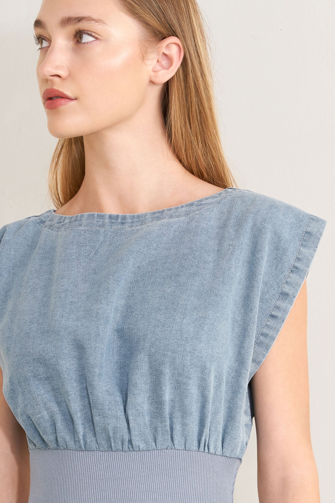 Woman wearing a denim jumpsuit featuring wide neckline, short sleeve, wide knit waistband, wide leg and back slit with button closure | FREEMARKET