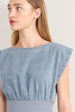 Woman wearing a denim jumpsuit featuring wide neckline, short sleeve, wide knit waistband, wide leg and back slit with button closure | FREEMARKET