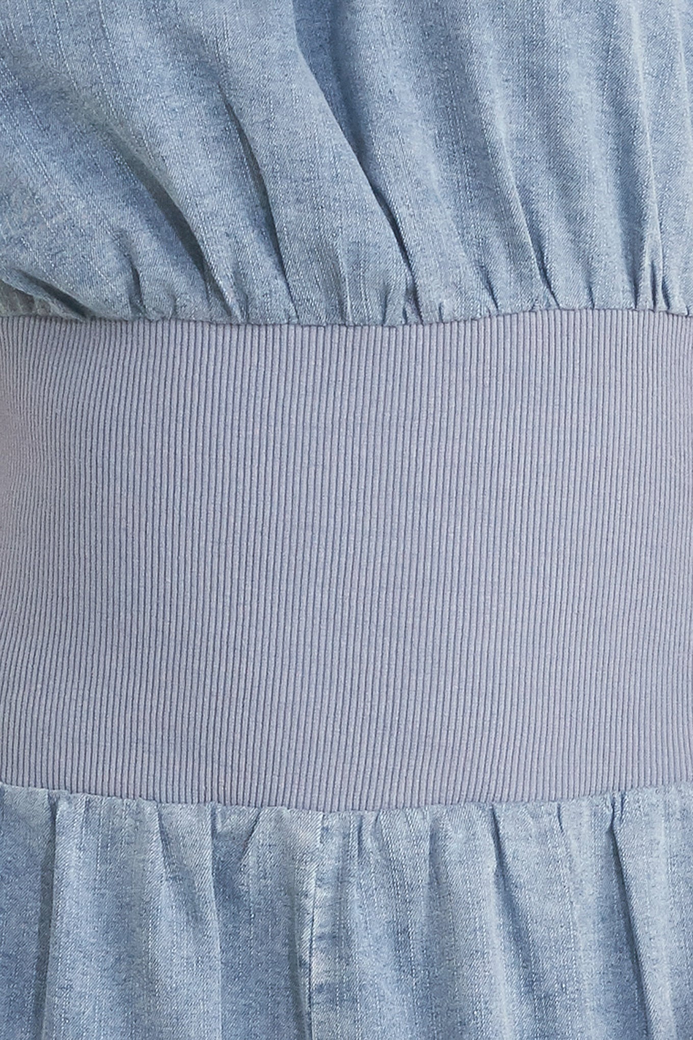 Close up of a denim jumpsuit featuring wide neckline, short sleeve, wide knit waistband, wide leg and back slit with button closure | FREEMARKET
