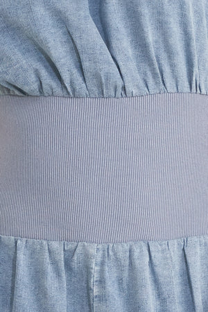 Close up of a denim jumpsuit featuring wide neckline, short sleeve, wide knit waistband, wide leg and back slit with button closure | FREEMARKET