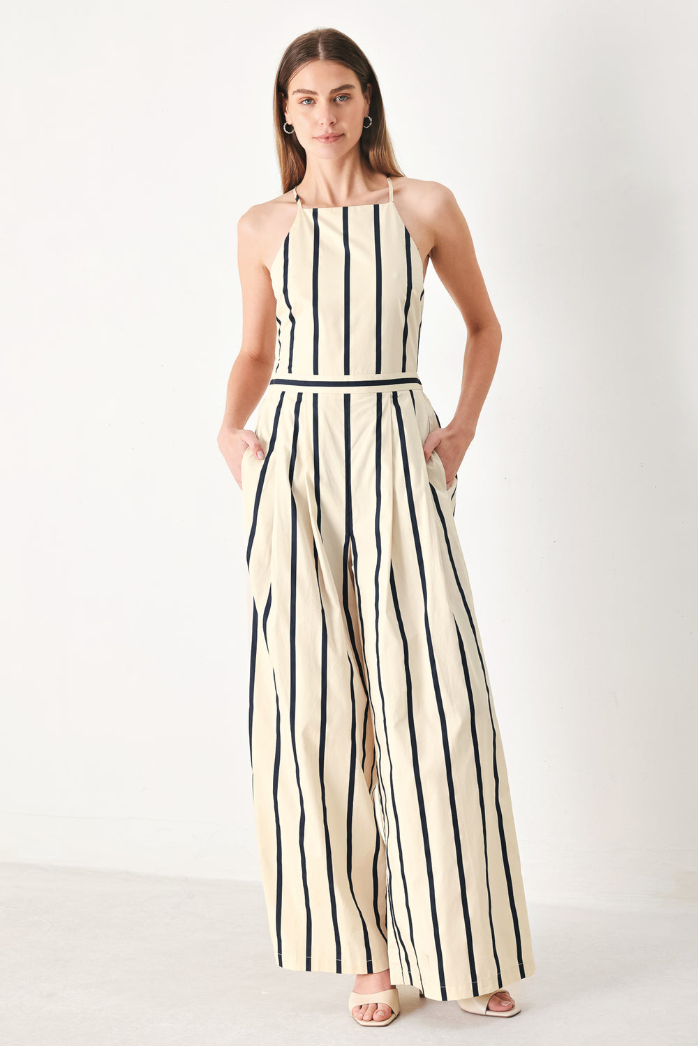 Woman wearing a navy and ivory striped  jumpsuit featuring straight neckline, side pockets, bare back with tie and wide leg | FREEMARKET | Flying Tomato