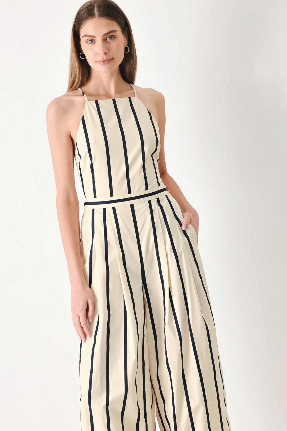 Woman wearing a navy and ivory striped  jumpsuit featuring straight neckline, side pockets, bare back with tie and wide leg | FREEMARKET | Flying Tomato