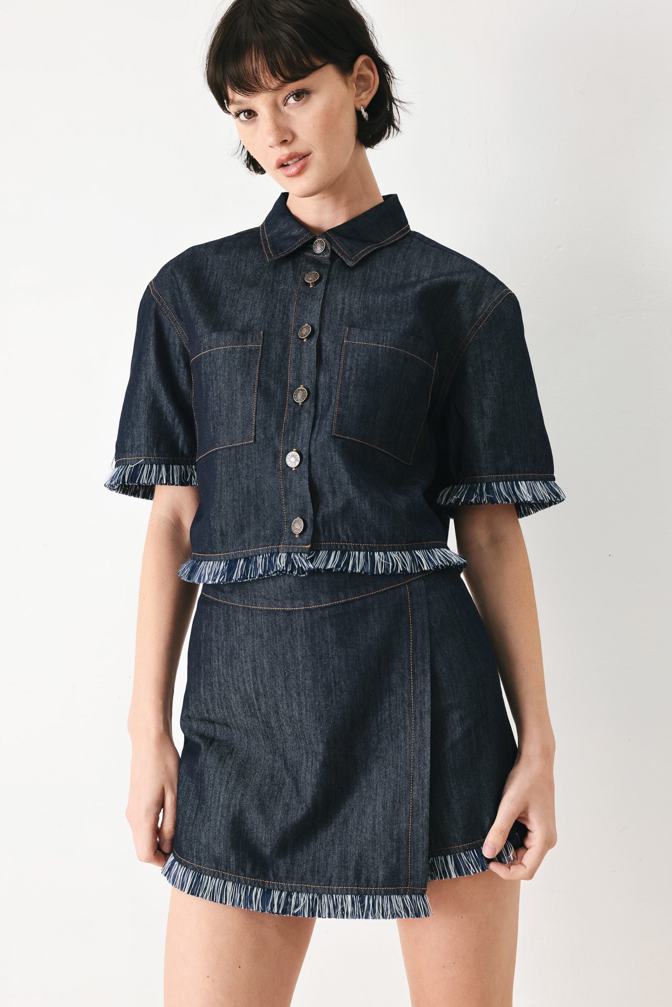 Woman wearing a dark denim skort featuring front flap, fray edge and back zipper closure | FREEMARKET