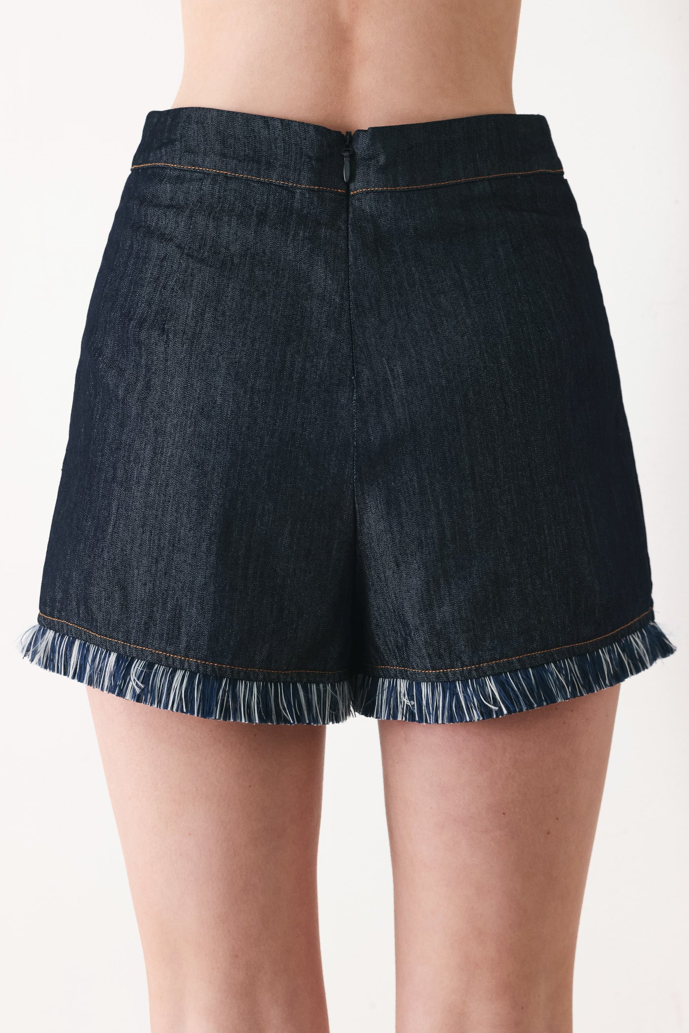 Woman wearing a dark denim skort featuring front flap, fray edge and back zipper closure | FREEMARKET